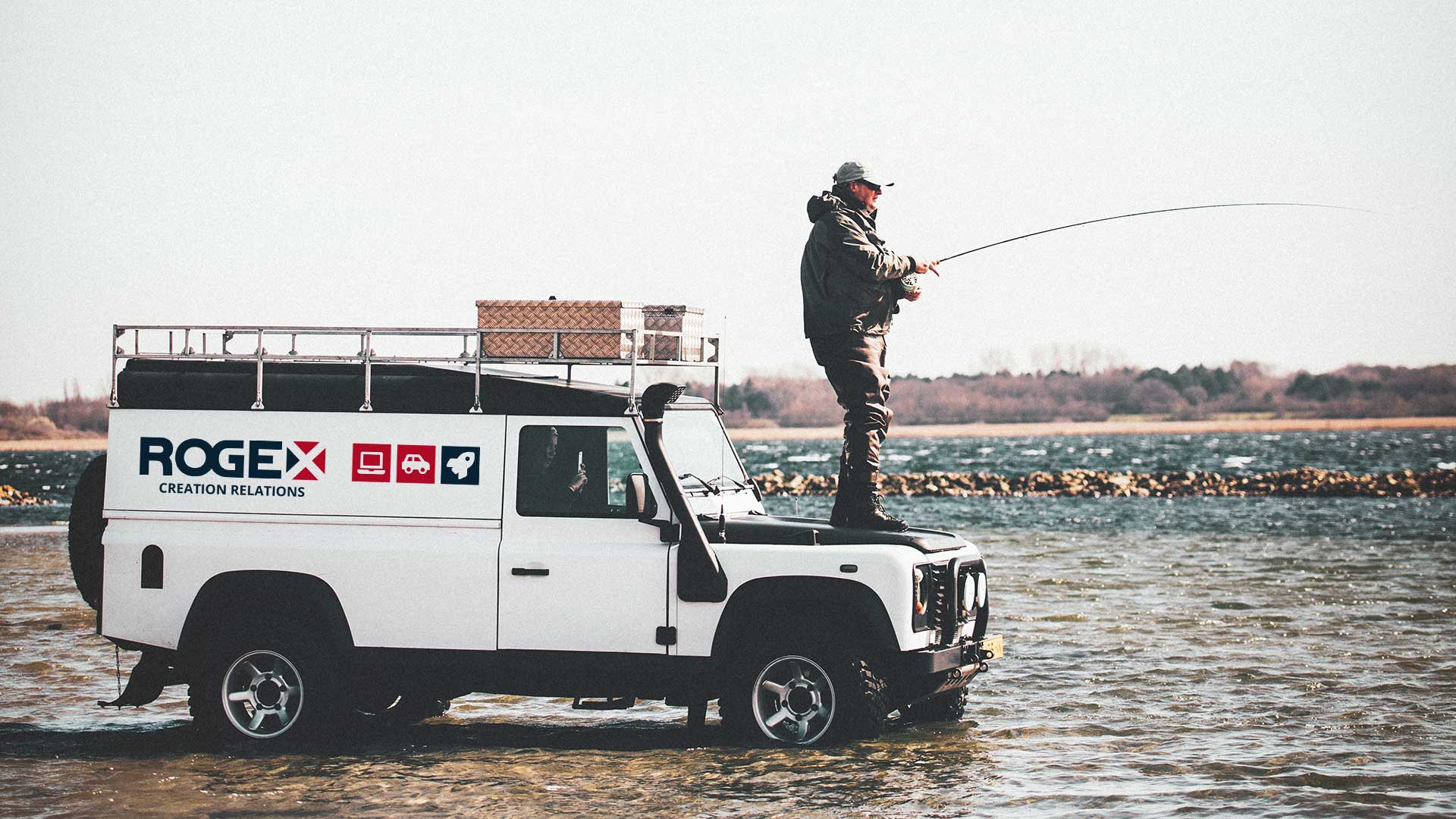 Defender aux couleurs de ROGEX dans l'eau, un pêcheur debout sur le capot
