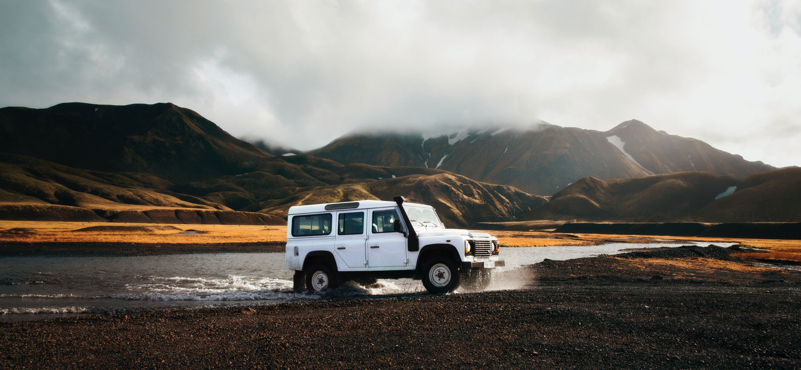 Defender blanc traversant une rivière au pied des montagnes